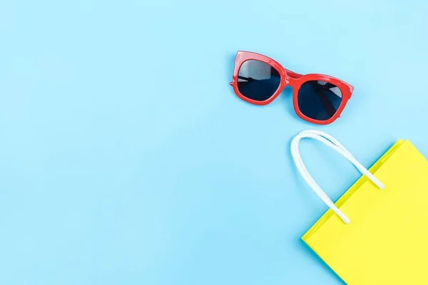 Bolsa Compras Papel Amarillo Gafas Sol Rojas Sobre Fondo Azul — Foto de Stock