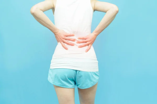 妇女的背身放在腰背或腰部有红斑 疼痛处有红斑 背痛在蓝色背景下孤立的保健概念 — 图库照片