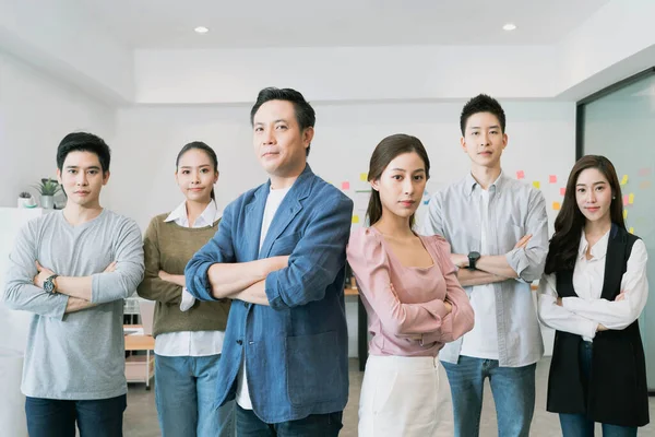 Group Portrait of young asian businesspeople standing indoors in office, looking at camera.Successful and confident business team with crossed arms