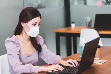 Korunma Corona gribi için koruyucu maske takan genç Asyalı iş kadını sağlıklı fikirler konsept ofisini engelliyor. Ofiste yeni normal yaşam tarzıyla yapılan çalışma.