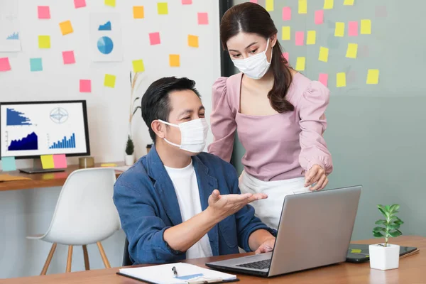 asian small business startup group wearing protective mask for covid19 protection corona flu prevent healty ideas concept office background.The work with new normal lifestyle in office.