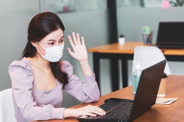 Korunma Corona gribi için koruyucu maske takan genç Asyalı iş kadını sağlıklı fikirler konsept ofisini engelliyor. Ofiste yeni normal yaşam tarzıyla yapılan çalışma.