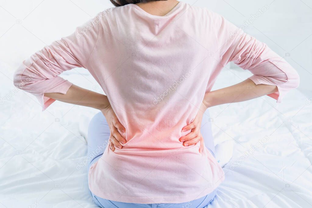 Attractive woman with back pain at home in the bedroom,This bed is not comfortable as I thought,female with waist pain