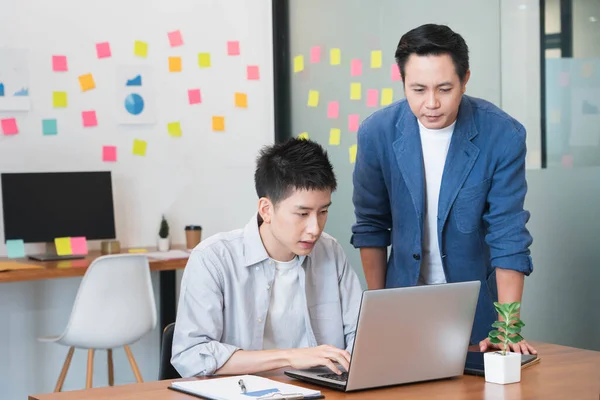 Senior male manager on the job training his colleague in the team for new project and work planning,teach trainee new worker learning new skill at workplace,supervising or teamwork concept