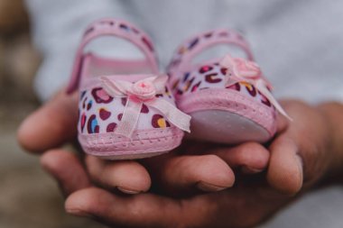 Küçük ayakkabılar, pembe bebek ayakkabıları tutan biri.