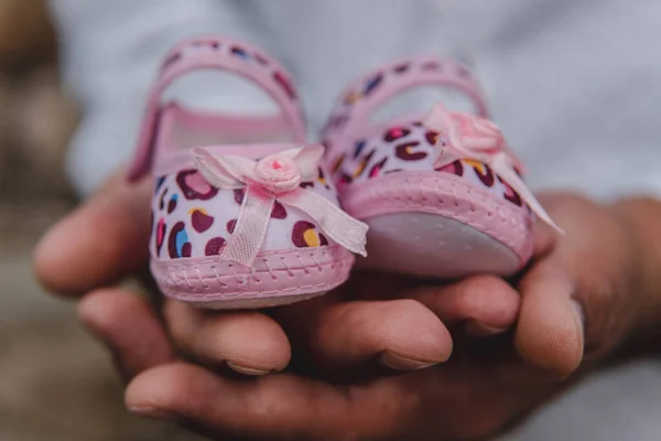 Küçük ayakkabılar, pembe bebek ayakkabıları tutan biri.