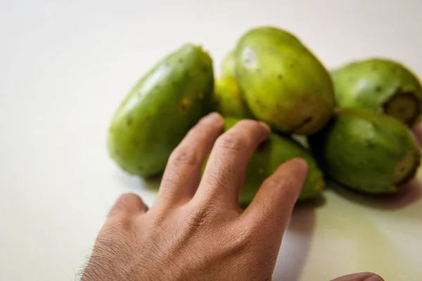 Beyaz arka planda dikenli bir armut alan erkek.