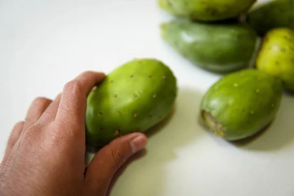 Beyaz arka planda dikenli bir armut alan erkek.