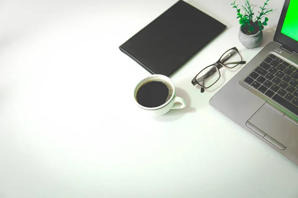 Çalışma alanı. Bilgisayar, kahve, bardak, bitki ve defter, beyaz bir alanda