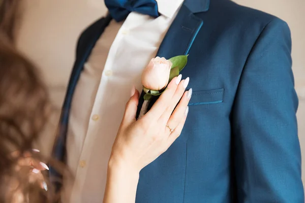 Рука Невесты Прикрепляет Бутоньерку Розой Куртке Жениха — стоковое фото