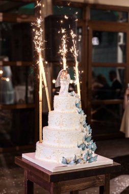 Beyaz düğün pastası dumansız tatil mumları ve kelebeklerle