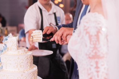 Gelin ve damadın ellerinde düğün pastasından bir parça kes. 