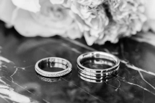 Svatební Prsteny Kytice Leží Tmavém Mramorovém Stole — Stock fotografie