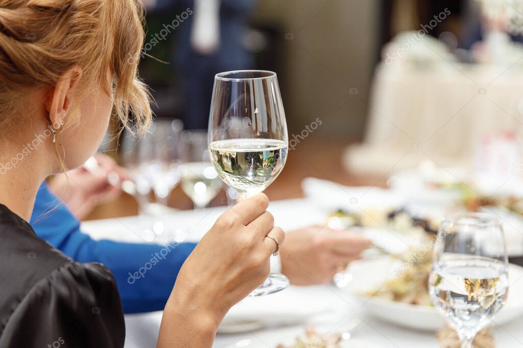 Glass of champagne in the hands of a girl at the festive table