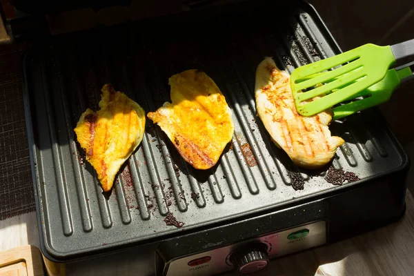 Carne é frita em uma grelha elétrica.Carne de bife grelhada em churrasco.frango com açafrão — Fotografia de Stock