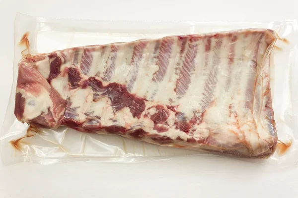 Süpürge, beyaz et üzerine izole edilmiş taze domuz pirzolası paketlemiş..