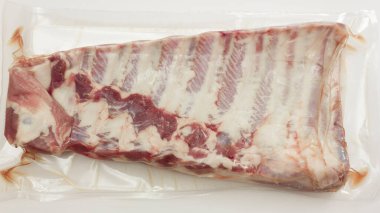 Süpürge, beyaz et üzerine izole edilmiş taze domuz pirzolası paketlemiş.