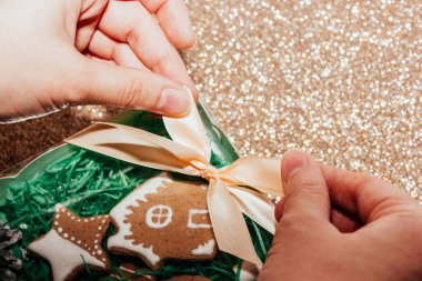 Kadın eli hediye olarak zencefilli kurabiye kutusuna fiyonk bağlar. Noel hediyesi.