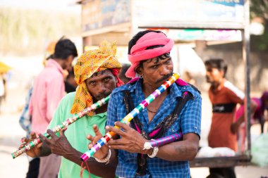 ALIRAJPUR, MADHYA PRADESH, İNDİYA, 15 Mart 2022: Hint bhil kabilesi davulda dans eden insanlar Bhagoria Festivali sırasında wiyh flüt çaldılar.
