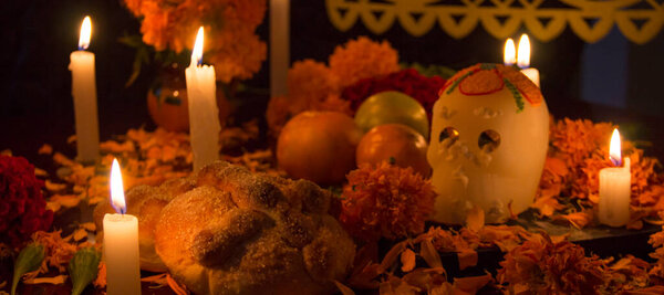 Сахарный череп со свечами, хлебом и цветами украшения на день умершего алтаря мексиканской традиции