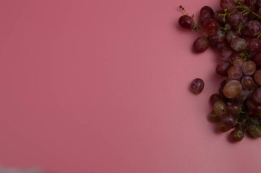 Pembe arka planda kırmızı üzümler
