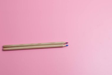 Pembe arka planda iki kalem.