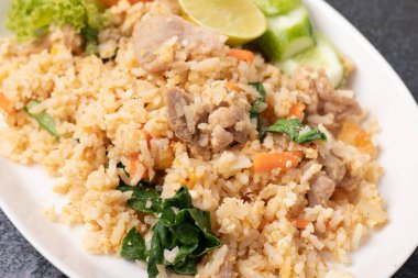 Siyah arka planda beyaz tabakta kızarmış domuz pirinci.