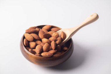 Kapatın. Beyaz arka planda tahtadan bir fincanda badem..