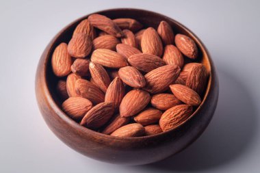 Kapatın. Beyaz arka planda tahtadan bir fincanda badem..