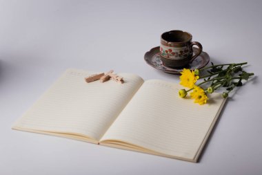 Kahve fincanları, ataçlar ve sarı çiçekler. Beyaz arkaplanda kopyalama alanı.