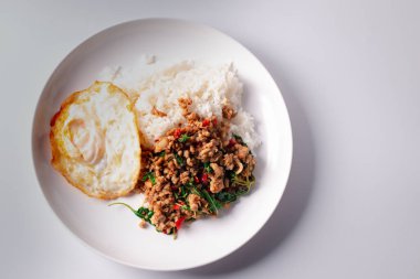 Beyaz arka planda beyaz bir tabakta sahanda yumurtalı domuz fesleğeni..