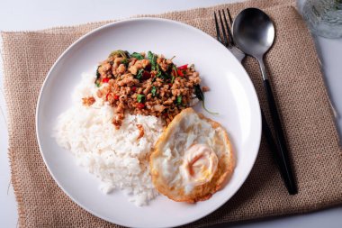 Beyaz arka planda beyaz bir tabakta sahanda yumurtalı domuz fesleğeni..