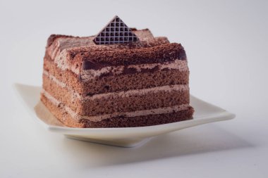Çikolatalı pasta beyaz arka planda bir tabakta katmanlanmış..