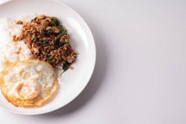 Beyaz arka planda beyaz bir tabakta sahanda yumurtalı domuz fesleğeni..