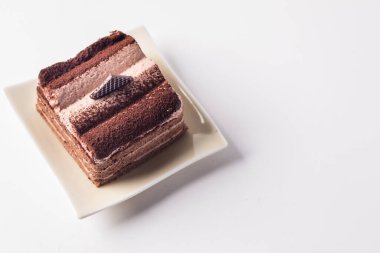 Çikolatalı pasta beyaz arka planda bir tabakta katmanlanmış..