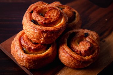 Kremalı tarçınlı puf böreği ve kuru üzümlü koyu ahşap arka plan. Üst görünüm, boşluk.