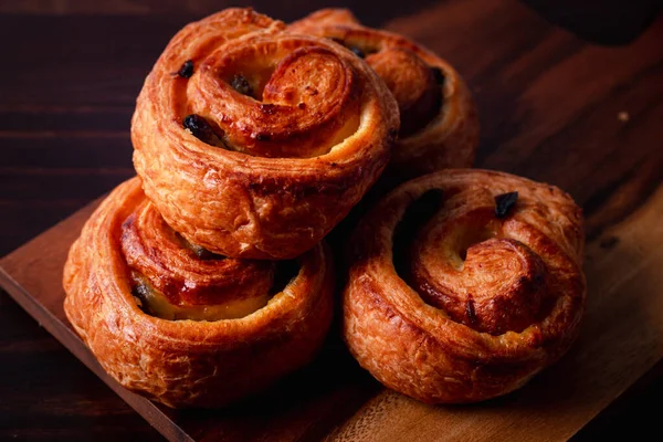 Kremalı tarçınlı puf böreği ve kuru üzümlü koyu ahşap arka plan. Üst görünüm, boşluk.