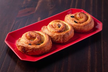 Muhallebi ile tarçınlı börek ve kuru üzümler koyu kırmızı plaka ahşap arka planda. Üst manzara, uzay..