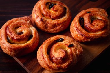 Kremalı tarçınlı puf böreği ve kuru üzümlü koyu ahşap arka plan. Üst görünüm, boşluk.