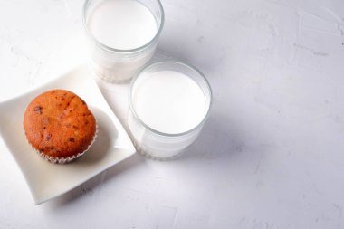 Siyah ve beyaz arka planda iki bardak sütü olan kekler.