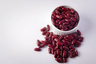 Beyaz arka planda beyaz seramik bir fincanda kırmızı fasulyeler.