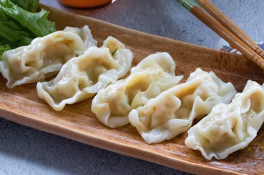 Masadaki kahverengi tabakta etli börekler.