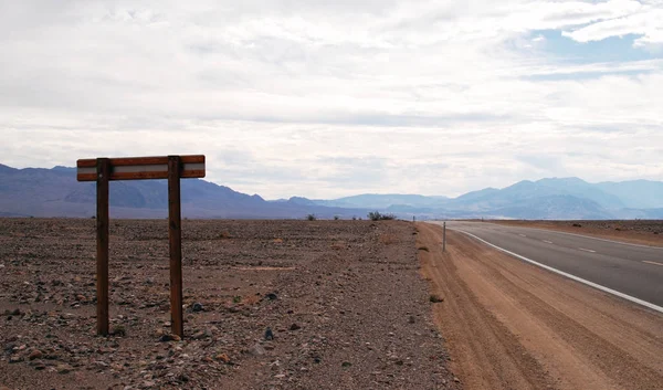 Señal de tráfico en una carretera a través del desierto Fotos De Stock Sin Royalties Gratis