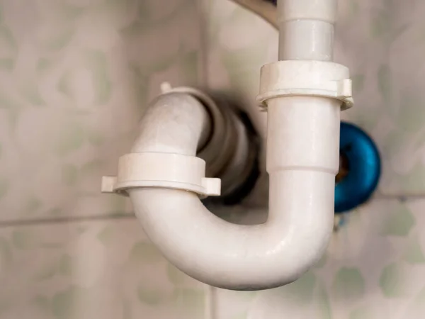 white bathroom drain pipe pipes and ceramic wall close-up