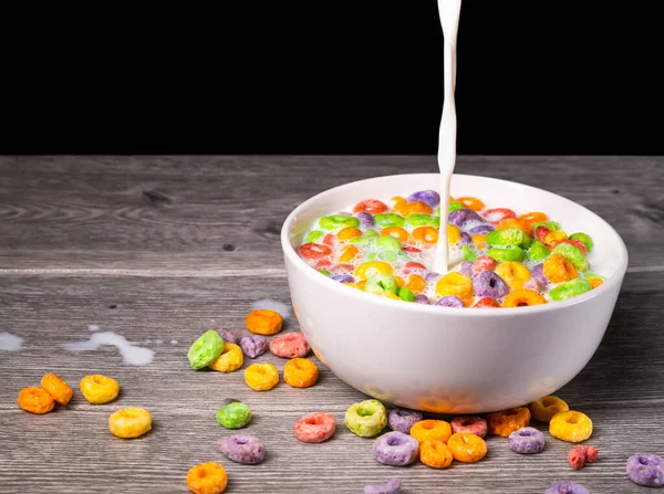 serving milk in a white bowl with colorful sugary cereal close-up