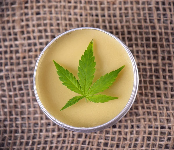 Detail of cannabis hemp cream with marijuana leaf over burlap background - cannabis topicals concept