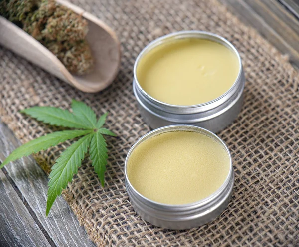 Cannabis hemp creams with marijuana leaf and nugs over burlap background - cannabis topicals concept