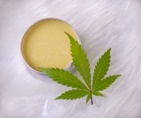 Cannabis hemp cream with marijuana leaf over white background - cannabis topicals concept