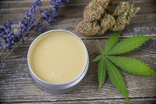 Cannabis hemp cream with marijuana leaf, lavender and nugs over wood background - cannabis topicals concept