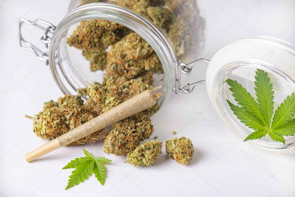 Cannabis buds and pre roll on clear glass jar isolated on white